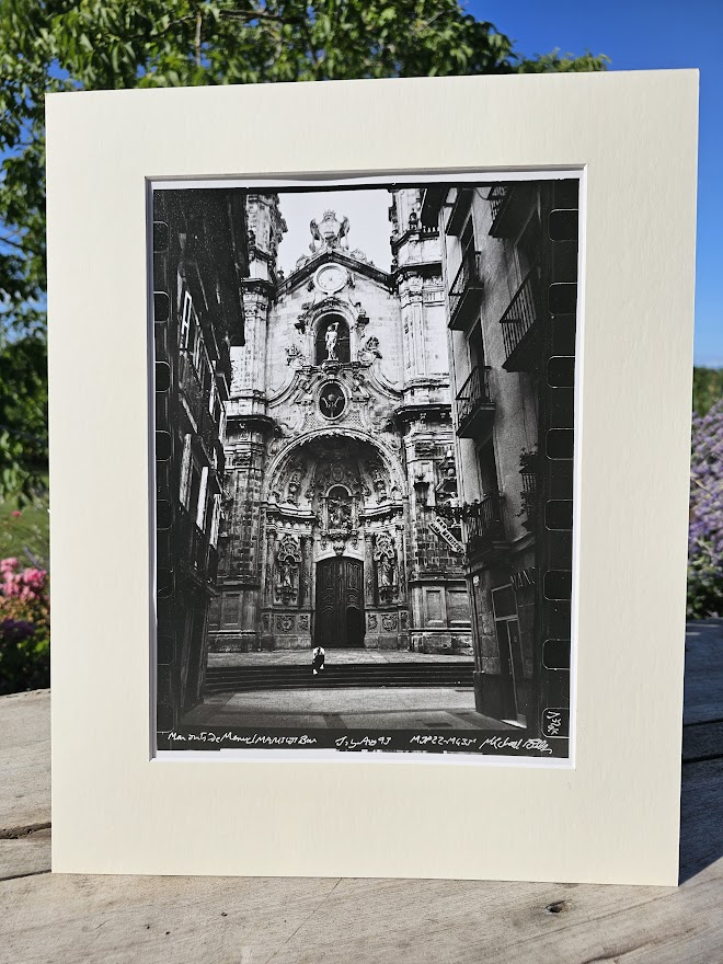 Homme assis devant la façade en pierre du bâtiment qui contient le bar Mariscos à Madrid par Michael Joseph