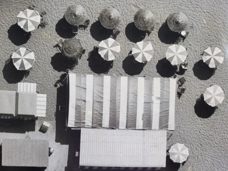 Aerial view of Cadaques beach, huts and parasols on a sunny day by Michael Joseph