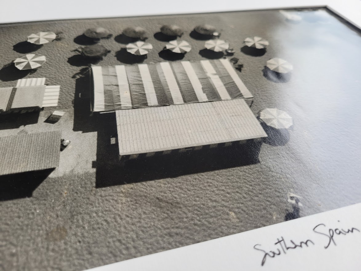 Aerial view of Cadaques beach, huts and parasols on a sunny day by Michael Joseph