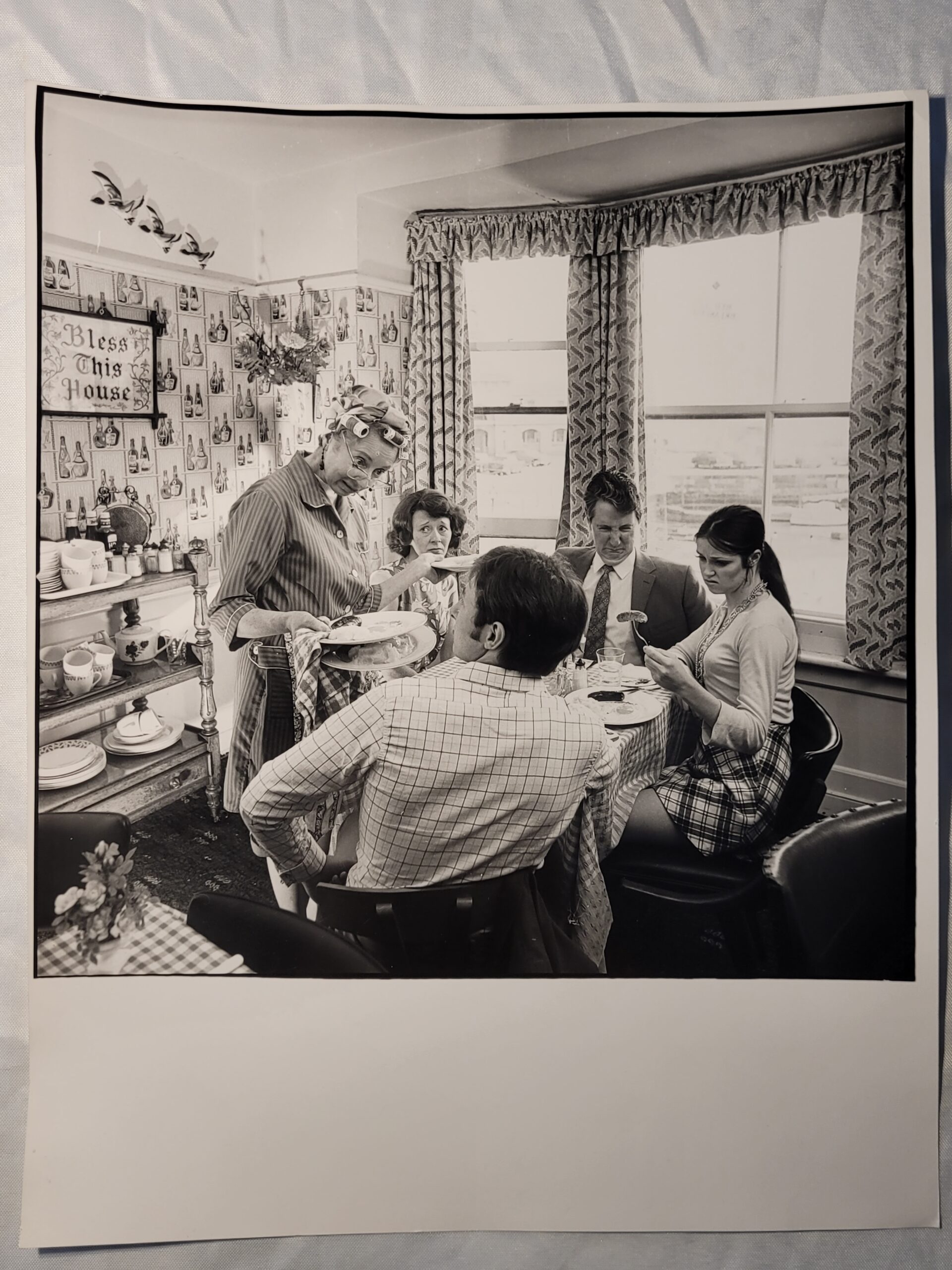 Family meal, housewife serving bangers and mash in curlers stereotypical british sixties household, by Michael Joseph