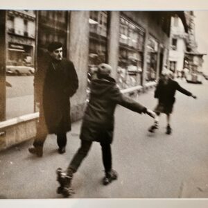 Pair of kids skating in parisian street with an onlooker in a beret by Michael Joseph