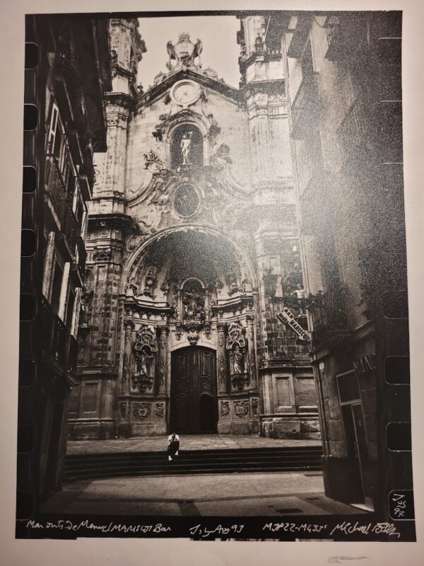 Homme assis devant la façade en pierre du bâtiment qui contient le bar Mariscos à Madrid par Michael Joseph