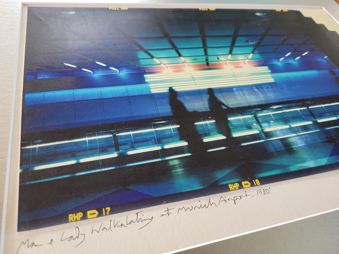 Silhouette d'un couple sur le trottoir roulant à l'aéroport de Munich, image à dominance bleue par Michael Joseph