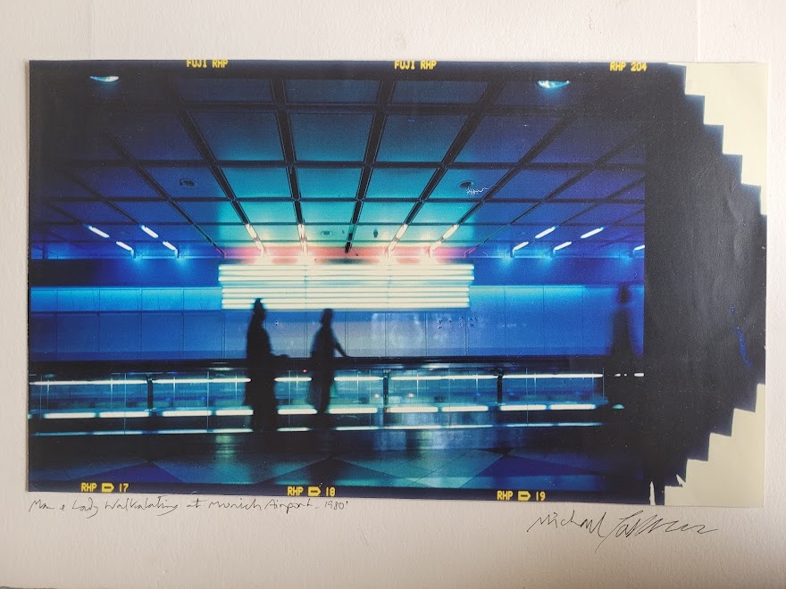 Silhouette d'un couple sur le trottoir roulant à l'aéroport de Munich, image à dominance bleue par Michael Joseph