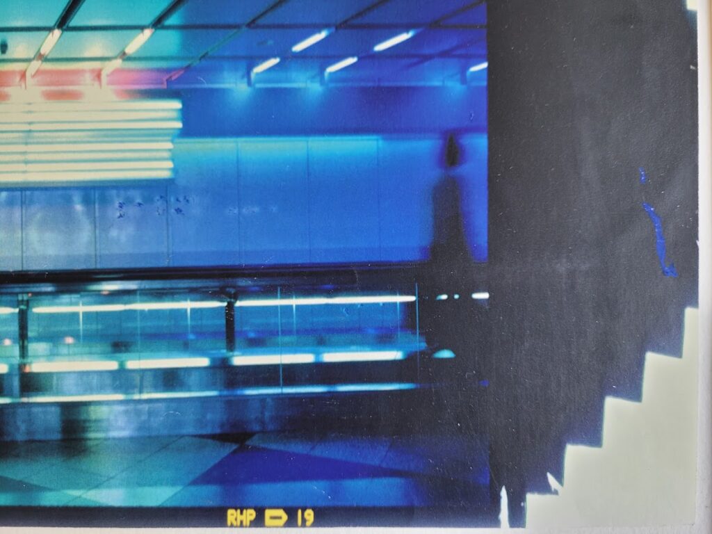 Silhouette d'un couple sur le trottoir roulant à l'aéroport de Munich, image à dominance bleue par Michael Joseph