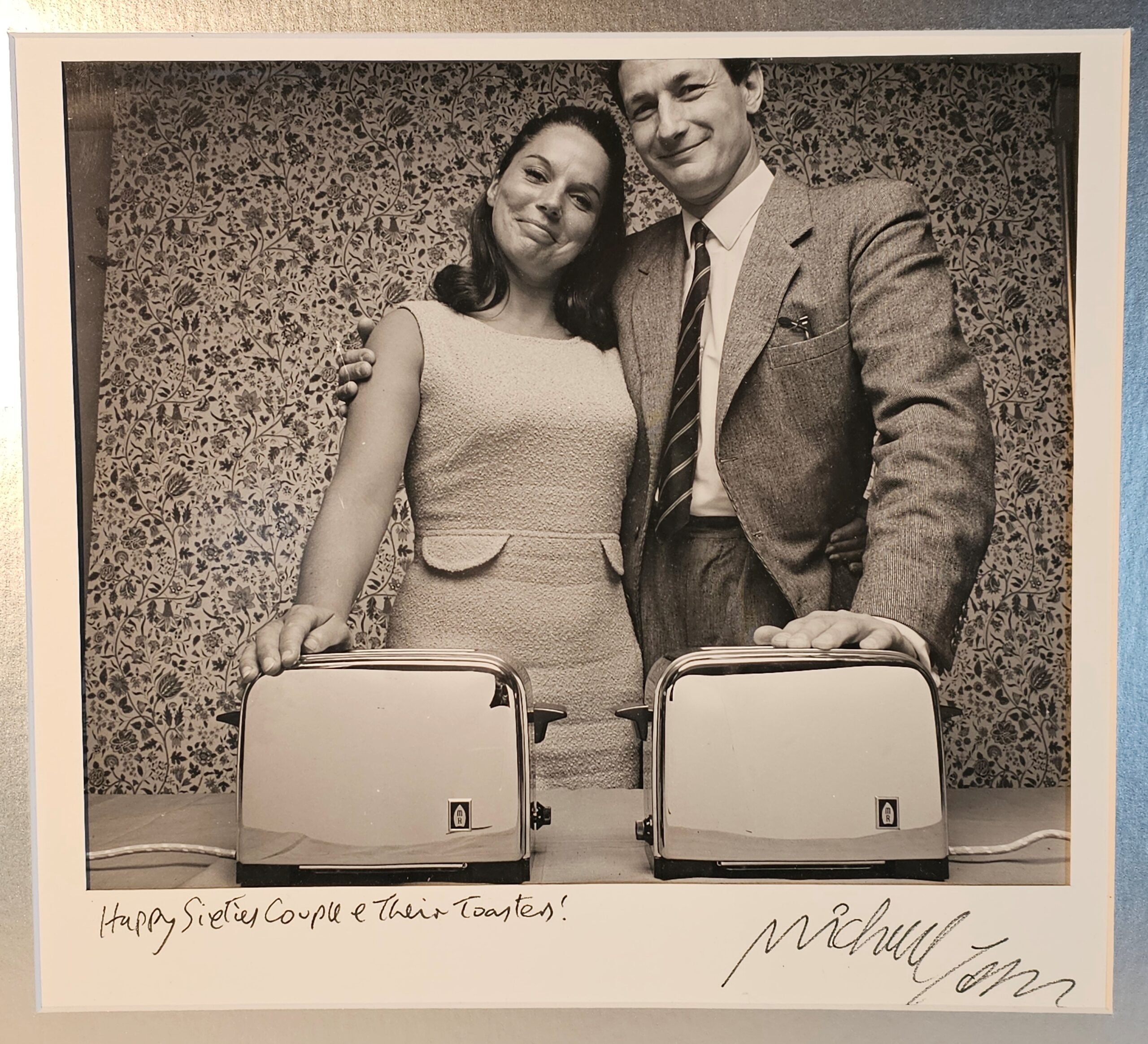 Sixties couple, smugly showing off their toasters with flowery wallpaper behind authentic darkroom print by Michael Joseph