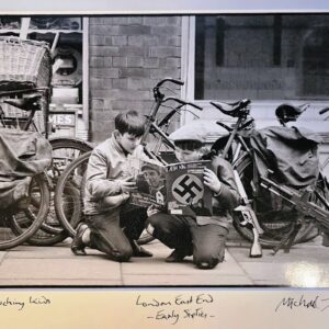 Boys reading Nazi magazine in East End London, kneeling on the pavement in the sixties by Michael Joseph