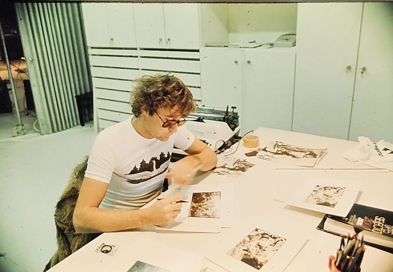 Michael Joseph sitting at a desk and studying photographic prints