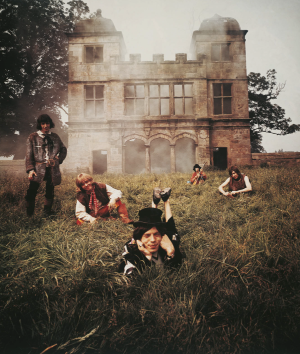 The Rolling Stones lying in a misty field in front of a ruined building